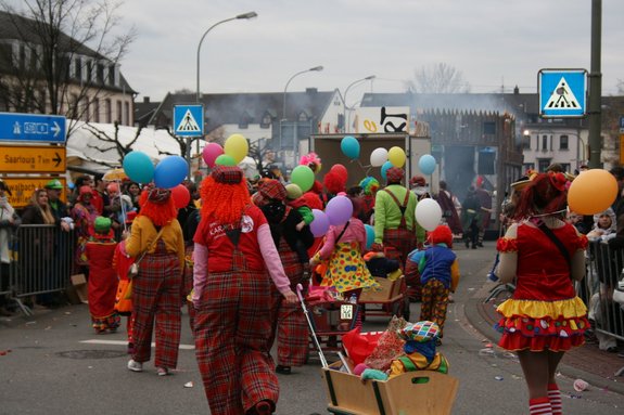 Rückansicht von verkleideten Clowns, welche die Straße entlang gehen