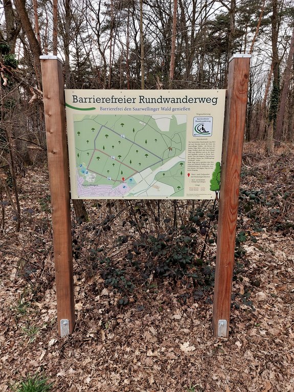 Das Bild zeigt die Hinweistafel am Eingang des barrierefreien Rundwanderweges am Freibad in Saarwellingen. Auf dem Schild ist ein Kartenausschnit zu sehen, auf welchem die beiden Wegoptionen für den Rundwanderweg eingezeichnet sind.