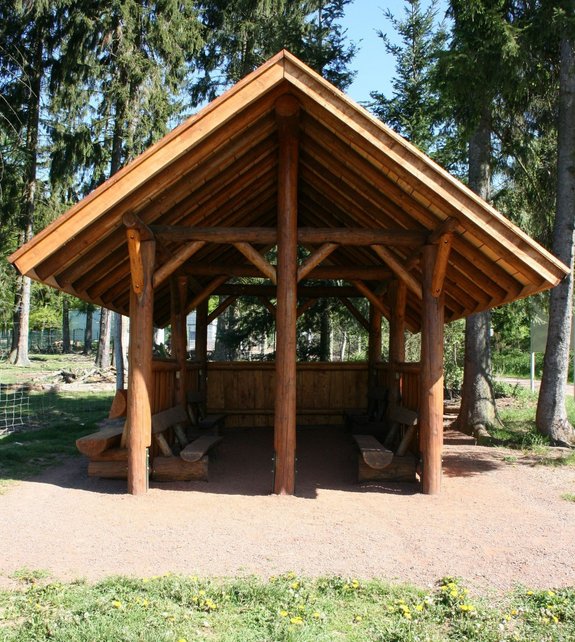 Das Foto zeigt eine Holzhütte mit Sitzmöglichkeiten im Wildfreigehege Wolfsrath in Saarwellingen. Hier kann man Rast machen bei einem Spaziergang.