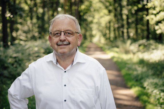 Frontansicht Bürgermeister Manfred Schwinn und im Hintergrund ein Waldweg